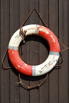 a life preserver hanging on the side of a wooden building with rope around it