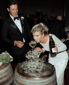 a man and woman standing next to each other in front of wine glasses