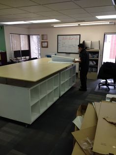 a man standing in an office with boxes on the floor and desks behind him