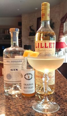 two bottles of liquor sitting on top of a counter next to a glass filled with liquid