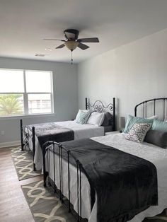 two beds in a room with a ceiling fan and carpeted flooring on one side