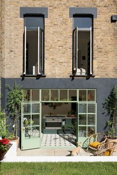 the front of a building with lots of windows and plants in pots on the lawn