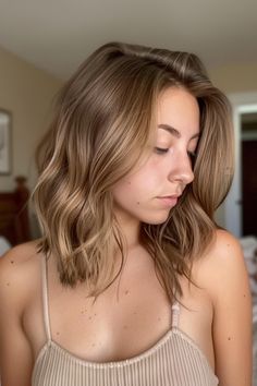 Woman with shoulder-length wavy hair, looking down in a softly lit room. Subtle Honey Highlights, Warm Blonde Lowlights, Light Brown Hair Color Ideas Honey, Lowlights On Medium Brown Hair, Subtle Highlights Light Brown Hair, Very Subtle Highlights Brunettes, Light Brown Hair Caramel, Honey Brown Hair With Blonde Highlights, Natural Balayage Light Brown