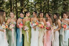 a group of women standing next to each other wearing dresses and holding bouquets in their hands