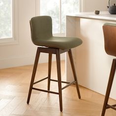 two wooden bar stools sitting next to each other in front of a kitchen counter