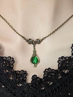 Welcome to our vintage-inspired world where elegance meets history! Dive into the allure of yesteryears with our Emerald Green Pendant Necklace, a timeless piece reminiscent of Victorian charm and historical costume jewelry. Crafted with meticulous attention to detail, this necklace features a captivating emerald green cats eye cabochon set in an elegant teardrop shaped antiqued brass pendant. Each pendant whispers tales of romance and elegance, capturing the essence of Victorian aesthetics. Emb Cheap Symbolic Green Jewelry, Shoulder Necklace Emerald, Cheap Elegant Green Necklaces, Cheap Green Vintage Necklace, Cheap Green Retro Necklace, Cheap Retro Green Necklace, Green Necklace Locket, Cheap Green Whimsical Necklaces, Medieval Jewelry Emerald