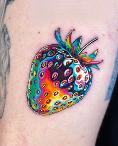 a colorful strawberry tattoo on the back of a woman's right arm, with dots all over it