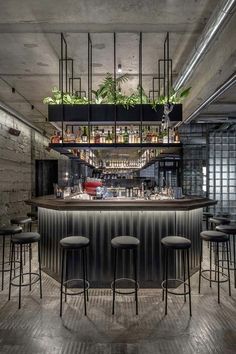 an industrial bar with stools and plants on the shelves