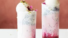 two glasses filled with ice cream and toppings on top of a white table next to each other