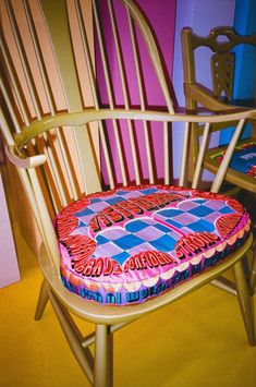 a wooden chair with a colorful cushion on it