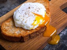 a piece of bread with an egg on it sitting on top of a cutting board