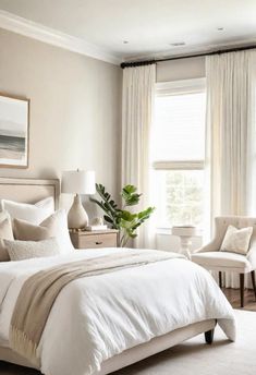 a white bed sitting in a bedroom next to two chairs and a window with curtains