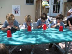 four boys sitting at a table with cups in front of them