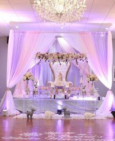 an elaborately decorated stage set up for a wedding reception with white drapes and flowers