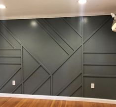 an empty room with wood flooring and gray painted wallpaper on the back walls