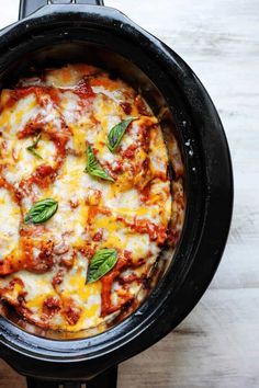 a close up of a pizza in a crock pot on a wooden table top