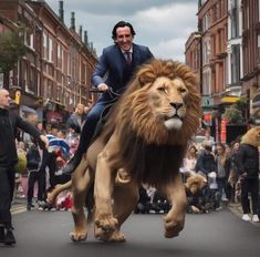 a man riding on the back of a large lion down a street next to people