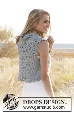 a woman is standing in the grass wearing a crochet top