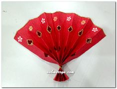 a red fan with gold and white designs on it