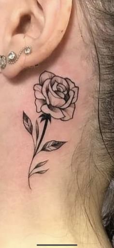 a woman's neck with a rose tattoo on her left side behind the ear