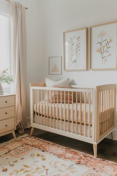 a baby's room with a crib, dresser and two pictures on the wall