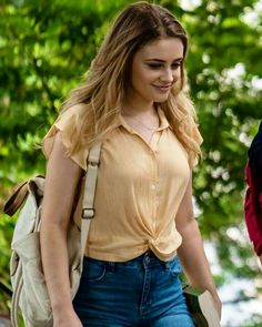 a young woman walking down the street with a backpack on her back and another person behind her