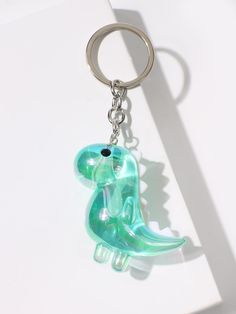 a glass keychain with a green and blue dinosaur on it's side