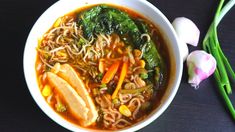 a white bowl filled with noodles, meat and veggies on top of a table