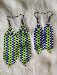 two green and blue beaded earrings on white fur