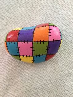 a colorful painted rock sitting on top of a white cloth covered floor next to a wall