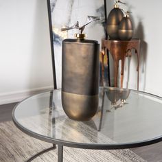 a glass table with a metal vase on it