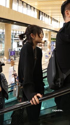 two people are standing on an escalator and one is looking at something in the distance