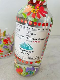 a bottle of alcohol sitting on top of a counter next to a glass bowl with candy in it