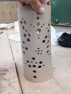 a person is making a vase out of clay with holes in the bottom and sides