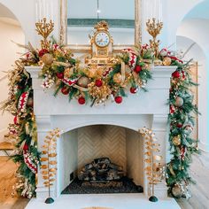 a fireplace decorated for christmas with garland and ornaments on it, along with a clock