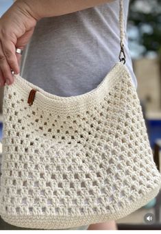 a woman holding a crocheted white purse