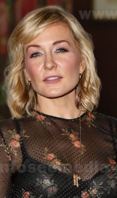 a woman with blonde hair wearing a sheer top and black floral print dress posing for the camera