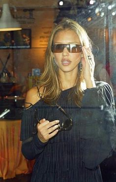 a woman wearing sunglasses and talking on her cell phone in front of a store window