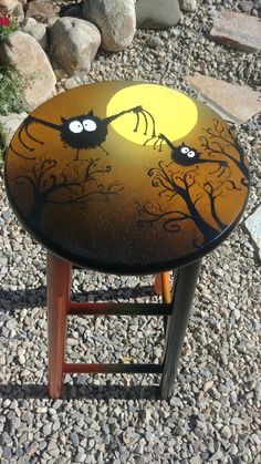 a painted stool with two black cats sitting on it's legs and one has a full moon in the background