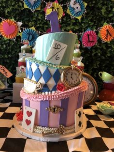 a multi - tiered cake decorated with colorful ribbons and clocks is displayed on a checkered tablecloth