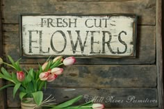 a sign that says fresh cut flowers and some pink tulips in a vase