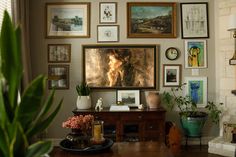 a living room filled with lots of pictures on the wall above a wooden coffee table