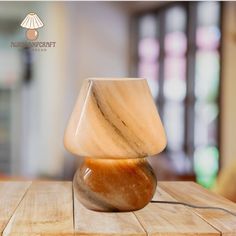 a marble lamp sitting on top of a wooden table next to a glass vase filled with liquid