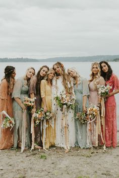 a group of women standing next to each other on a beach with flowers in their hair