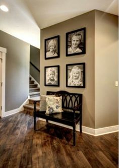 a room with pictures on the wall and a bench in front of it next to stairs