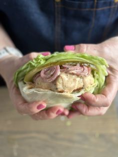 a person holding a sandwich with meat and lettuce