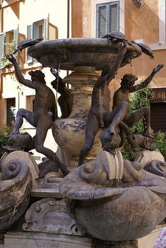 a fountain with several statues around it in front of a building