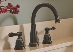 a black faucet with gold trim and two handles on a white countertop