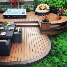 a hot tub sitting on top of a wooden deck next to a lush green field