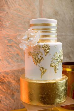 a white and gold wedding cake with flowers on top